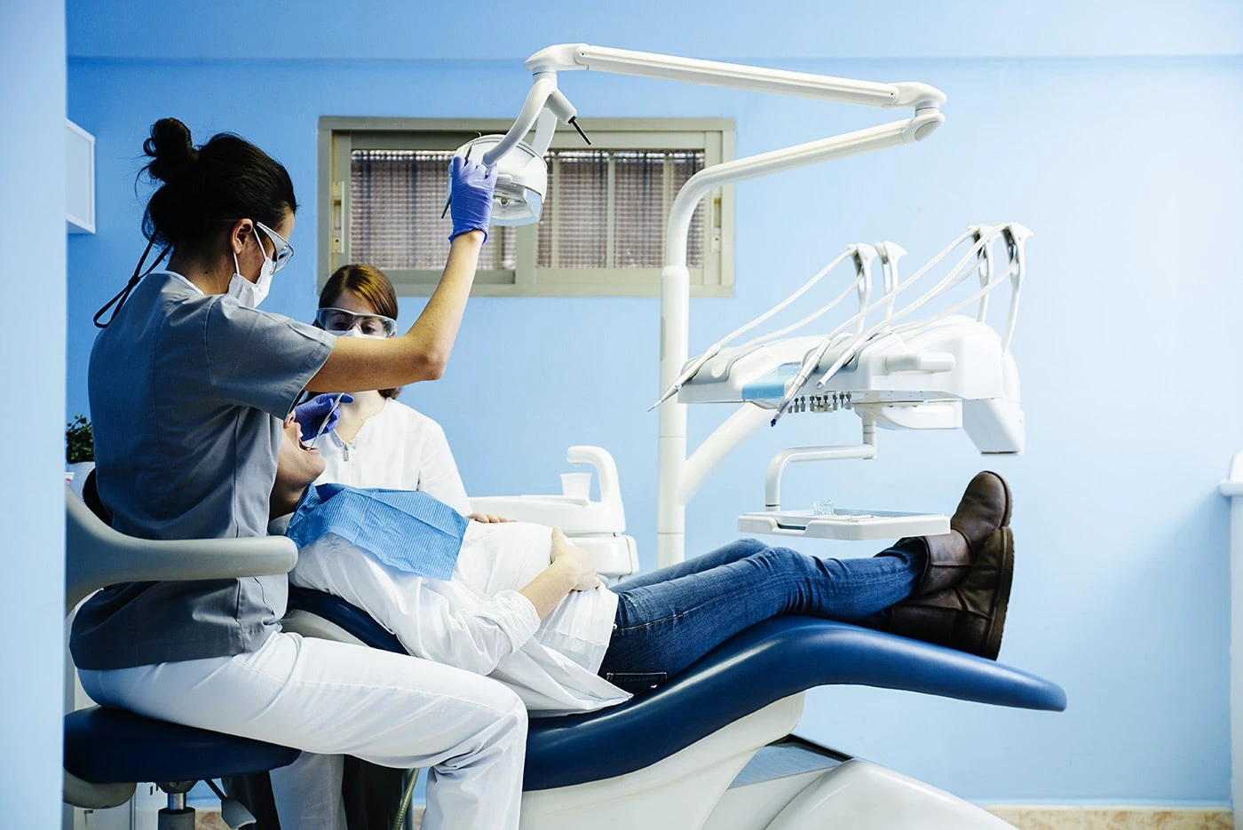 A dental surgeon, assistant, and patient in a dental chair with surgical tools, showcasing expertise and precision in the procedure.